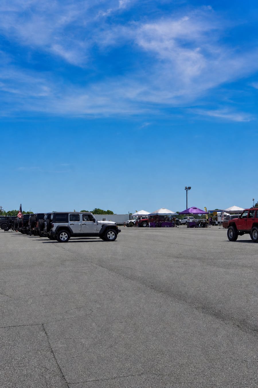 Silver Jeep Wrangler at the head of a line of rigs with the big Davie County sky overhead.